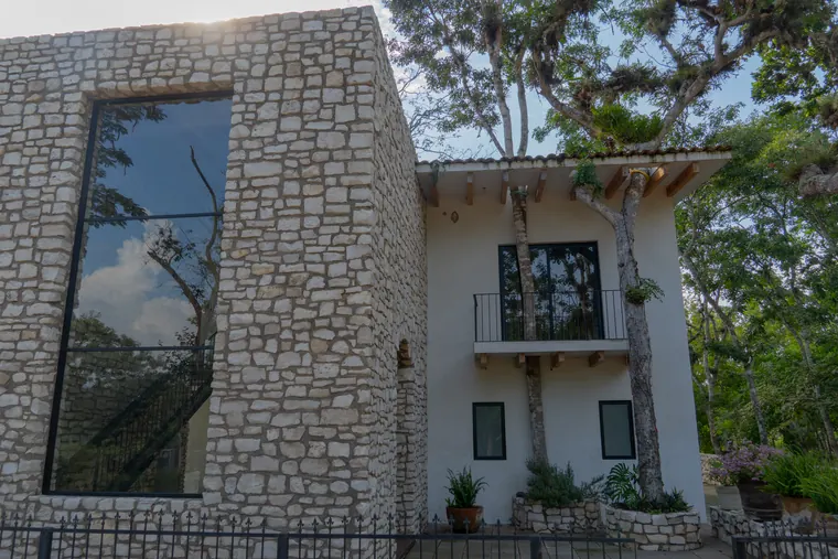 Torre de piedra y ala blanca de la casa entre árboles