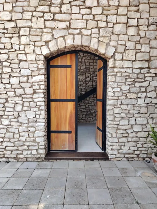 Portón de madera abierto en un muro de piedra de San Lorenzo